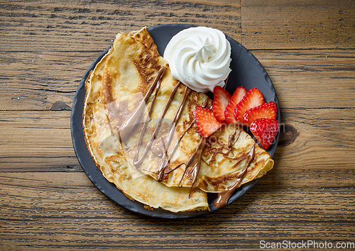 Image of freshly baked crepes with whipped cream and strawberries