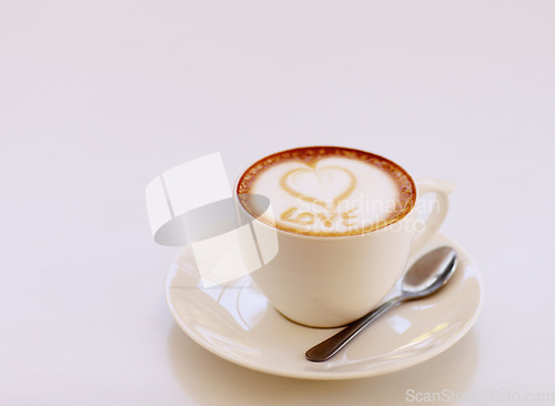 Image of Coffee cup, cappuccino and heart in foam in studio isolated with white background. Cafe drink, love writing and foamy beverage art with milk and mockup with a closeup of mug, message and spoon