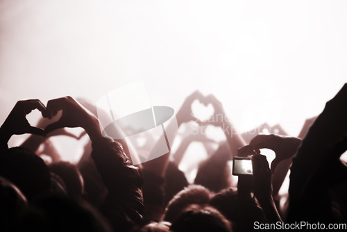 Image of Hands, heart and phone in the audience with people watching a concert or music festival event. Party, dance or disco with a group of men and women in the crowd while attending a stage performance