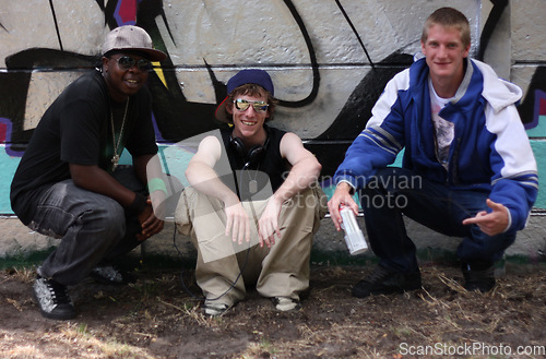 Image of Graffiti, street art and portrait of friends by wall with spray can for hip hop, fashion and urban. Smile, artist and painting with group of male teenagers in park for grunge, creative and style