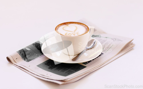 Image of Coffee cup, cappuccino and newspaper with heart in foam on a table with no people in a restaurant. Cafe drink, love writing and foamy beverage art with milk in a latte and a closeup of mug and spoon