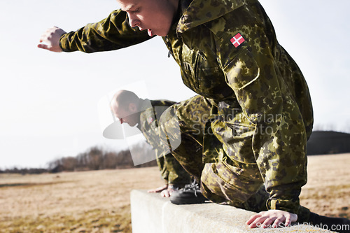 Image of Soldier in training, military men and jump over a wall in obstacle course for fitness and endurance. Army team in camouflage uniform outdoor, train for war and exercise with mission and action