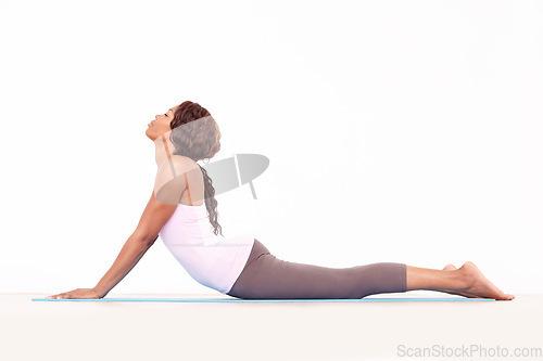 Image of Yoga, cobra back stretch and black woman relax in studio on a fitness and workout mat for training. Isolated, white background and calm African female person lying on the ground with body stretching