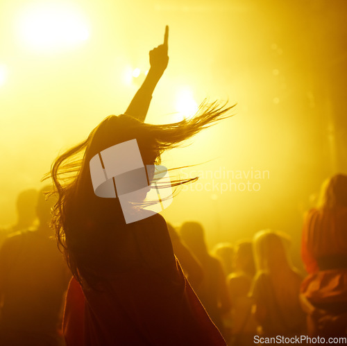 Image of Dance, rave and female person at a concert, disco event or psychedelic trance festival. Night, energy and woman dancing or moving to a song with a yellow light at techno night club or party with dj.