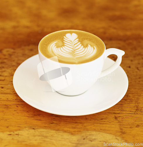 Image of Coffee, cafe and latte art in a cup on wooden table background in restaurant to drink espresso with foam. Retro, diner and mug with saucer in kitchen with vintage design during morning breakfast.