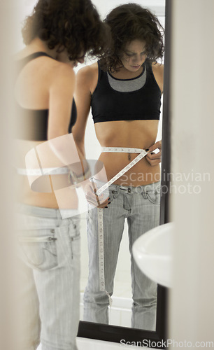Image of Anorexia, tape and sad woman in mirror for eating disorder, anxiety and mental health. Depression, weight loss and measuring with female and reflection at home for body image, bulimia and sick