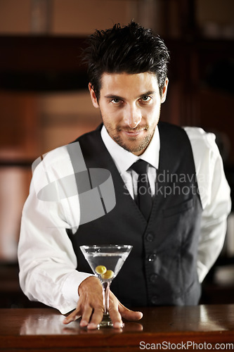 Image of Man, portrait and giving cocktail at bar for service, drink and welcome to party, club or event. Male server, barman or waiter with glass for alcohol, spirit or mixer with presentation at restaurant