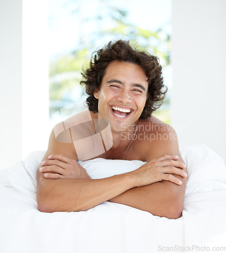 Image of Laughing, portrait and a handsome man in bed for sleep, relaxing and rested in the morning. Wake up, resting and a guy in bedroom looking cheerful after sleeping or nap in the comfort of a house