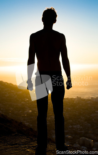 Image of Man, silhouette and mountain in sunset for achievement, adventure or hiking journey in nature. Male hiker standing on cliff for trekking exercise view, accomplishment or motivation for fitness goals