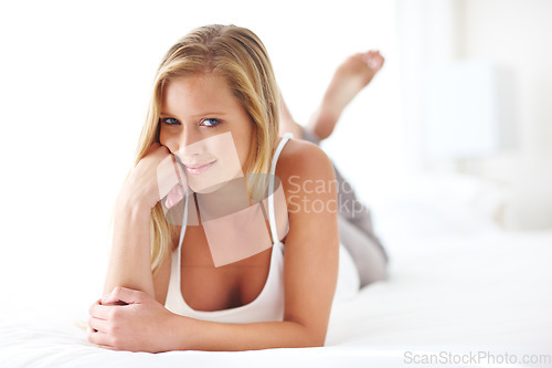 Image of Relax, portrait and casual woman on a bed, resting and satisfied with a peaceful indoor morning. Face, smile and female lying down on the weekend, chilling and relaxed on day off in a bedroom