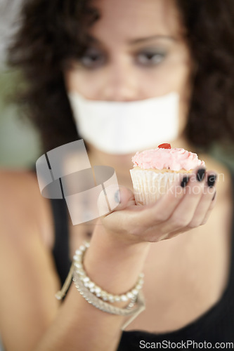 Image of Cupcake in hand, eating disorder and a woman on diet and tape over mouth to stop or lose weight. Face, covering and restriction of female suffering with anorexia, body dysmorphia or bulimia problem