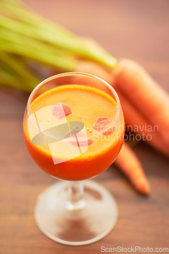 Image of Carrot juice, vegetable and healthy food or drink with color, art and nutritionist creativity. Vegan smoothie or orange liquid in glass for wellness, diet or nutrition on a wooden table with ice