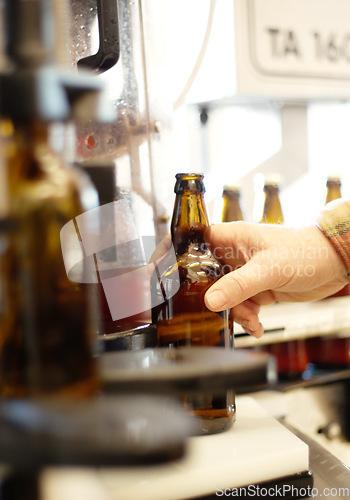 Image of Hands, beer and bottle in factory, brewery or manufacturing plant for quality inspection. Alcohol, production line and person taking glass from automatic conveyor machine with product in warehouse.