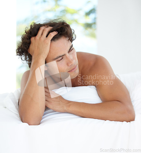 Image of Young, man and model in bed thinking in apartment for happiness and calm life in home. Man, focus and bedroom with hand in hair with idea for wellness and healthy living in house with sunshine.