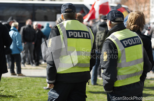 Image of Law enforcement, safety and crowd control with police officer in city for peace, security or authority. Emergency services, justice and guard with person in Denmark street for rally, order and arrest