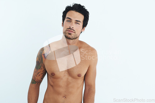 Image of Portrait, body and muscle with a sexy man in studio on a white background for masculine desire. Shirtless, tattoo and manly with a handsome young male model posing topless for rugged sensuality