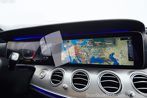 Image of View from inside a car on a part of dashboard with a navigation unit and blurred street in front of a car