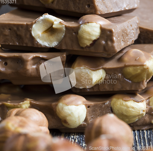Image of bitter real chocolate, photographed close-up with whole hazelnuts inside and next to a bar of broken chocolate