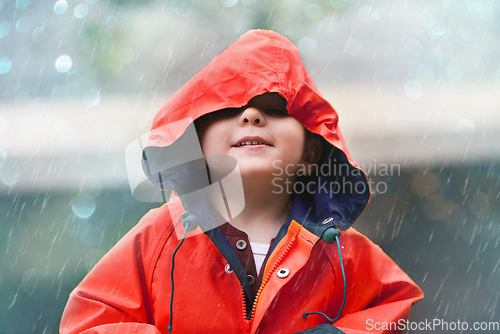 Image of Happy boy, red raincoat and little child playing or having fun with the raindrops and outdoors. Smile, kid and looking up at the sky or enjoying rainfall and showers on bokeh background