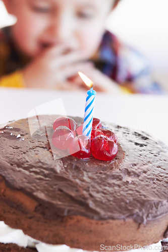 Image of Birthday cake closeup, young kid and celebration candle with dessert at home with a child. Chocolate, cherry and candles to celebrate a boy at a party with sweets on a kitchen table in a house