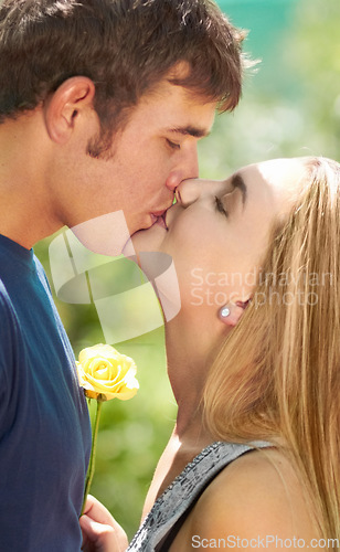 Image of Love, kiss and happy with couple in nature for romantic, bonding and affectionate. Happiness, flowers and gift with man and woman kissing in garden park on date for spring, care and valentines day