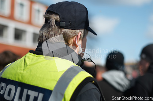 Image of Law enforcement, protection or crowd control with police officer in city for peace, safety and authority. Emergency services, justice and guard with back of person in street at rally, order or arrest