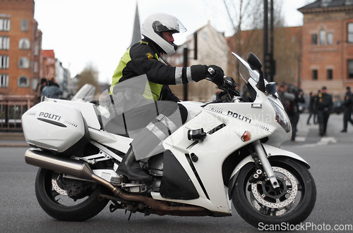 Image of Police, motorcycle and safety officer working for protection and peace in an urban neighborhood in the UK. Security, law and legal professional or policeman on a motorbike ready for service