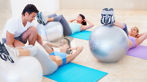 Image of Personal trainer, pilates and ball for helping women with balance, posture and happy for training, fitness and gym. Man, exercise and help woman in class with stretching, wellness or workout on floor