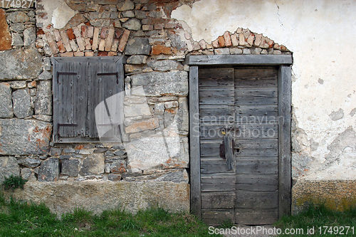 Image of Wooden door and window on stone facade.