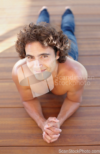 Image of Portrait, topless and a man lying on a wooden deck outdoor in summer to relax or rest during the day. Sexy, shirtless and hot with a handsome young male person resting on a wood floor from above