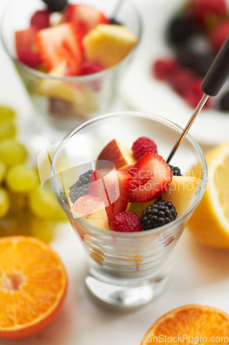 Image of Fruit salad, breakfast and healthy food or diet in studio with color, art and creativity. Nutritionist, wellness and fruits for vegan snack with berry, apple and orange ingredient on a white table