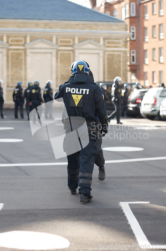 Image of Security, authority and back of police officer in the city working to patrol a protest or march. Law enforcement, public service and safety guard in uniform for protection in an urban town street.