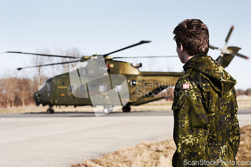 Image of Army, military or soldier man with a helicopter outdoor for transportation, Denmark war and pilot mission. Male person for combat, flight or air force service in camouflage uniform to watch or patrol