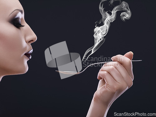 Image of Makeup, hot and woman blowing a spoon with steam in studio with gothic, cool and danger aesthetic. Mockup, art and female posing with smoke and utensil creative, punk and edgy on black background