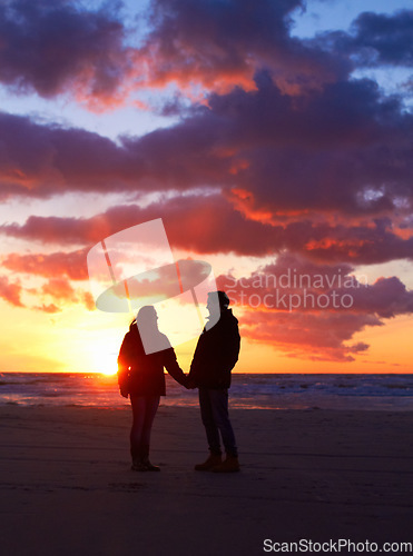 Image of Couple, silhouette and sunset sky at the beach on a romantic date, vacation or holiday in nature. Man and woman holding hands with love and care on travel, adventure or trip with clouds and ocean