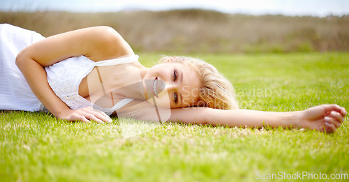 Image of Portrait, rest and a woman lying on grass outdoor in nature during summer for peace or quiet on a field. Spring, garden and relax with a young person relaxing outside on green ground in a countryside