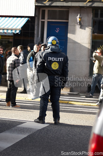 Image of Safety, crowd control and protest with police officer in city for law enforcement, protection or security. Brave, uniform and riot with person in Denmark street for rally, human rights or activist