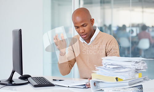 Image of Stress, documents and burnout with a business black man in an office, sitting at a desk while working on a problem. Audit, tax and compliance with a young male employee suffering from anxiety at work