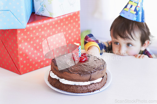 Image of Birthday cake, kid and curious of food at party with gifts and dessert at home with a hungry child. Chocolate, sneaky and snack to celebrate a boy at a party feeling temptation for sweets in house