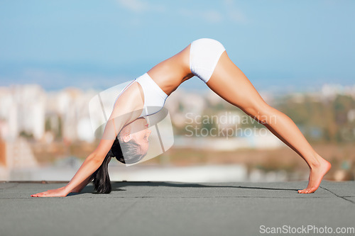 Image of Woman, yoga and stretching on roof top in city for exercise, workout or fitness outdoors. Female yogi in warm up stretch for healthy body, wellness or training in balanced lifestyle in an urban town