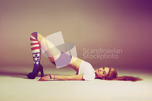 Image of Portrait of sexy woman on floor with socks, fashion and retro style on studio background and American flag. Beauty, underwear and aesthetic influencer or model lying on ground in vintage mockup space