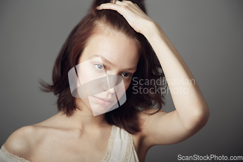 Image of Sad woman, stress and anxiety with hand on hair in mental health problem isolated on a grey studio background. Anxious, stressed or depressed young female model holding head in thought on backdrop