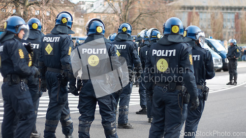 Image of Law, security and back of police in city during a protest or march for protection and public service. Safety, violence and professional guards in uniform working in urban town street for peace patrol