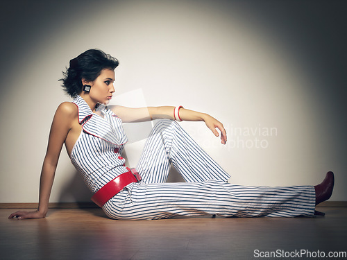 Image of Spotlight, fashion and gen z girl on a studio floor with attitude, style and cool against a wall background. Edgy, cool and fashionable female model relax in designer outfit, beautiful and unique