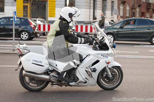 Image of Police, motorbike and road safety officer working for protection and peace in an urban neighborhood in Denmark. Security, law and legal professional or policeman on a motorcycle ready for service