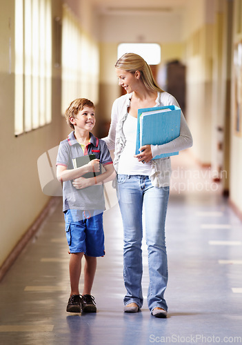 Image of Teacher, child and walking in corridor at school, talking and bonding together. Education, smile and woman walk with kid, boy or student in hallway while going to class, speaking and discussion.