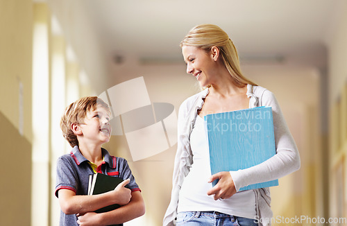 Image of Talking, teacher and boy walking, hallway and happiness with advice, help and education. Male child, student and woman with a smile, lobby and conversation with joy, communication and development