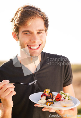 Image of Portrait, smile and a man eating food outdoor on a summer day for health, diet or nutrition. Happy, morning and lifestyle with a handsome young person enjoying a fresh meal alone outside in nature