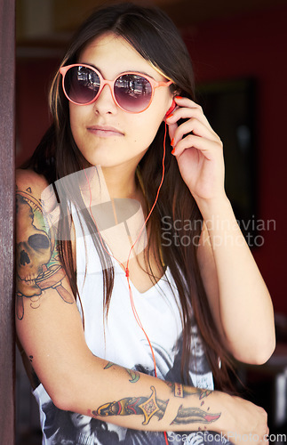 Image of Tattoo, earphones and punk gen z woman with urban fashion or style relax while listening to music online. Podcast, radio and unique female person streaming audio or rock in summer with freedom