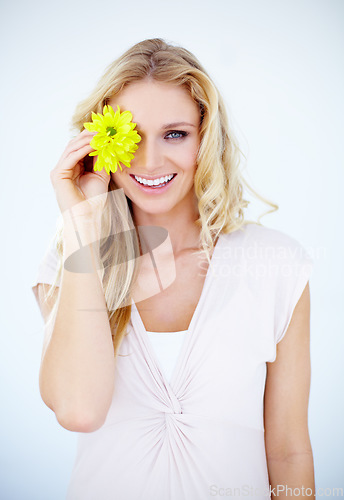 Image of Beauty, happy and portrait of a woman with a flower in a studio with a cosmetic, natural and face routine. Makeup, smile and female model with a yellow floral plant isolated by a white background.